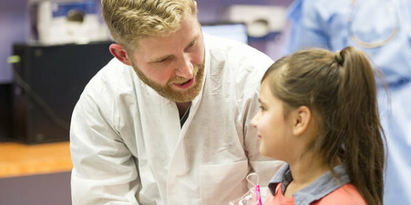 Pediatric dentistry resident Dr. Benjamin Curtis discusses with his young patient what will soon happen with her teeth.