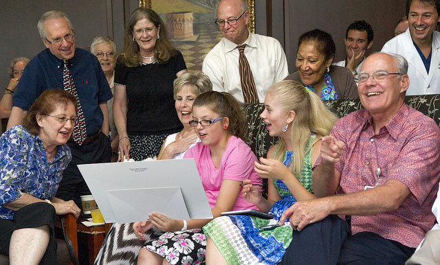 Family, friends and co-workers look at an old photo given to Dr. Dean Hudson, right, during his June 30 retirement reception.