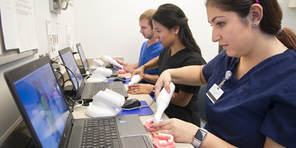 Lorena Campos, Alyssa Dawson, and Zac Carlson use CAD/CAM during the D2 preclinical fixed lab.