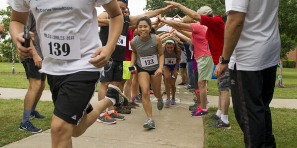 Runners run through a tunnel created by people interlocking their hands.
