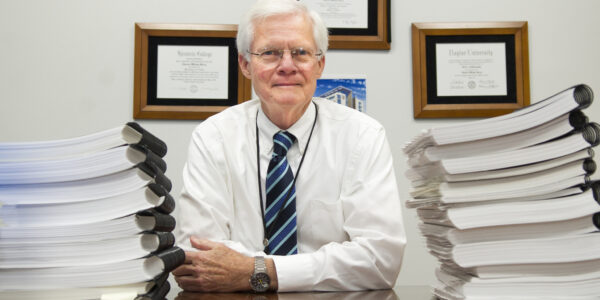 Dr. Charles Berry sits amid stacks of accreditation self study papers