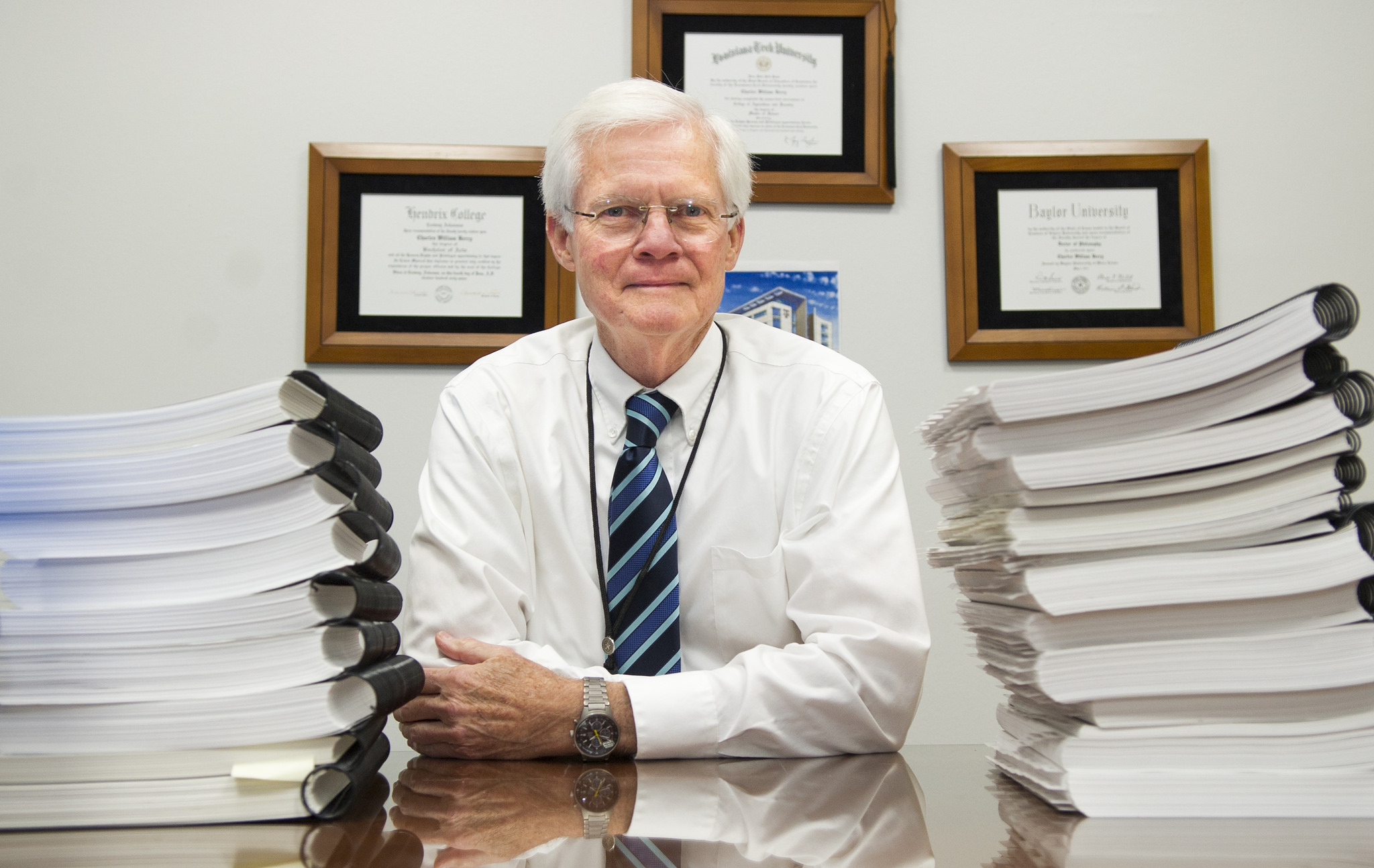 Dr. Charles Berry sits amid stacks of accreditation self study papers