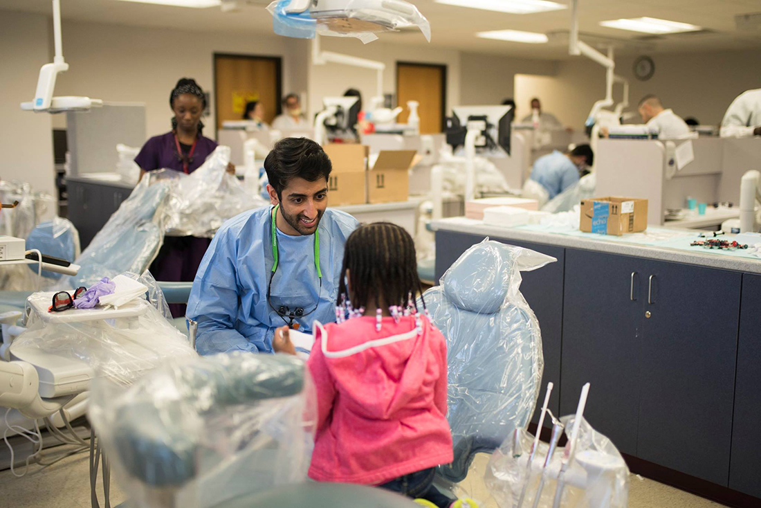 A dental student talks with a pediatric patient during Give Kids a Smile at Texas A&M College of Dentistry.