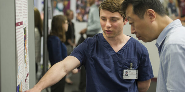 Pekar discusses his poster with Dr. Xiaofang Wang during the College of Dentistry's April 5 Research Scholars Day.