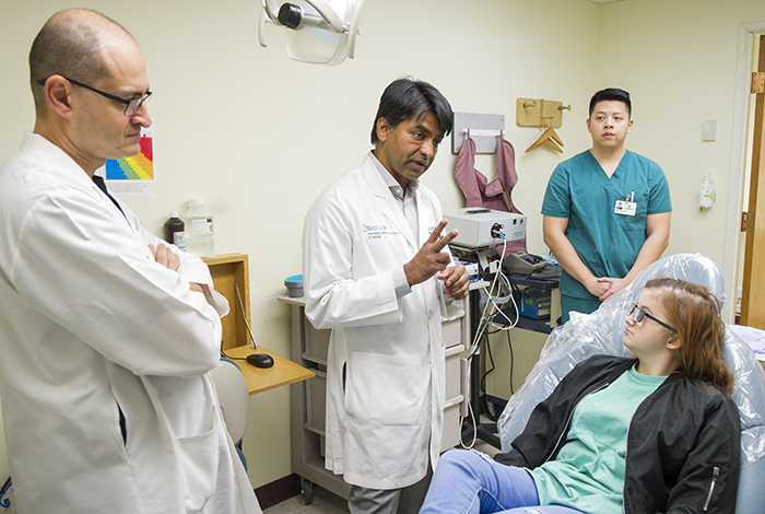 Dr. Likith Reddy, center, and Dr. Amirali Zandinejad, left, consult with Hannah McCain during an appointment at Texas A&M College of Dentistry in December 2017.
