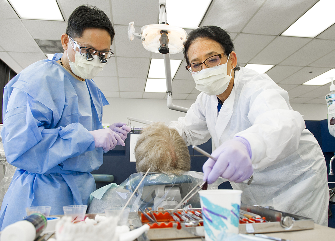 Dr. Minh Nguyen, left, and Dr. Amerian Sones treat a patient in the Continuing Education Dental Implant Continuum in spring 2016.