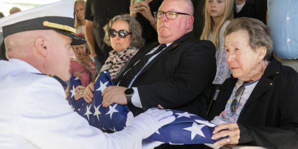 Marian Rogers accepts husband Paul Rogers' ceremonial flag from a U.S. Navy representative.