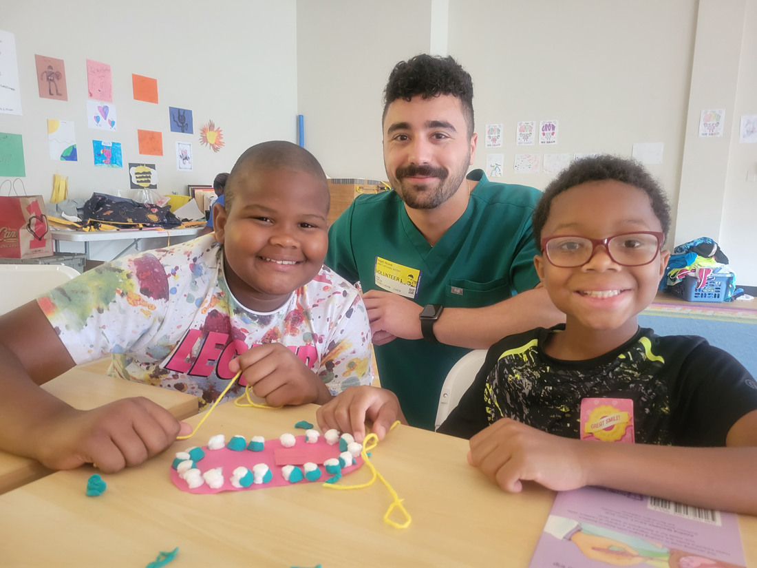 Children learn about proper flossing technique with the help of dental student James Needy. 
