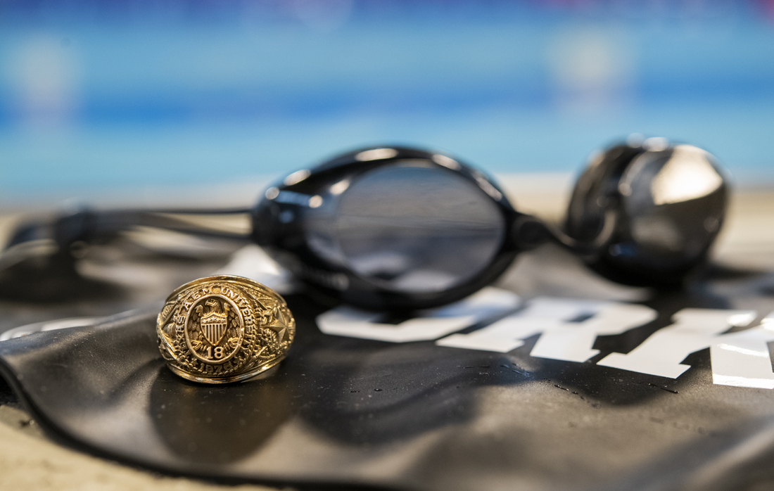 A picture of swimming goggles next to an Aggie ring