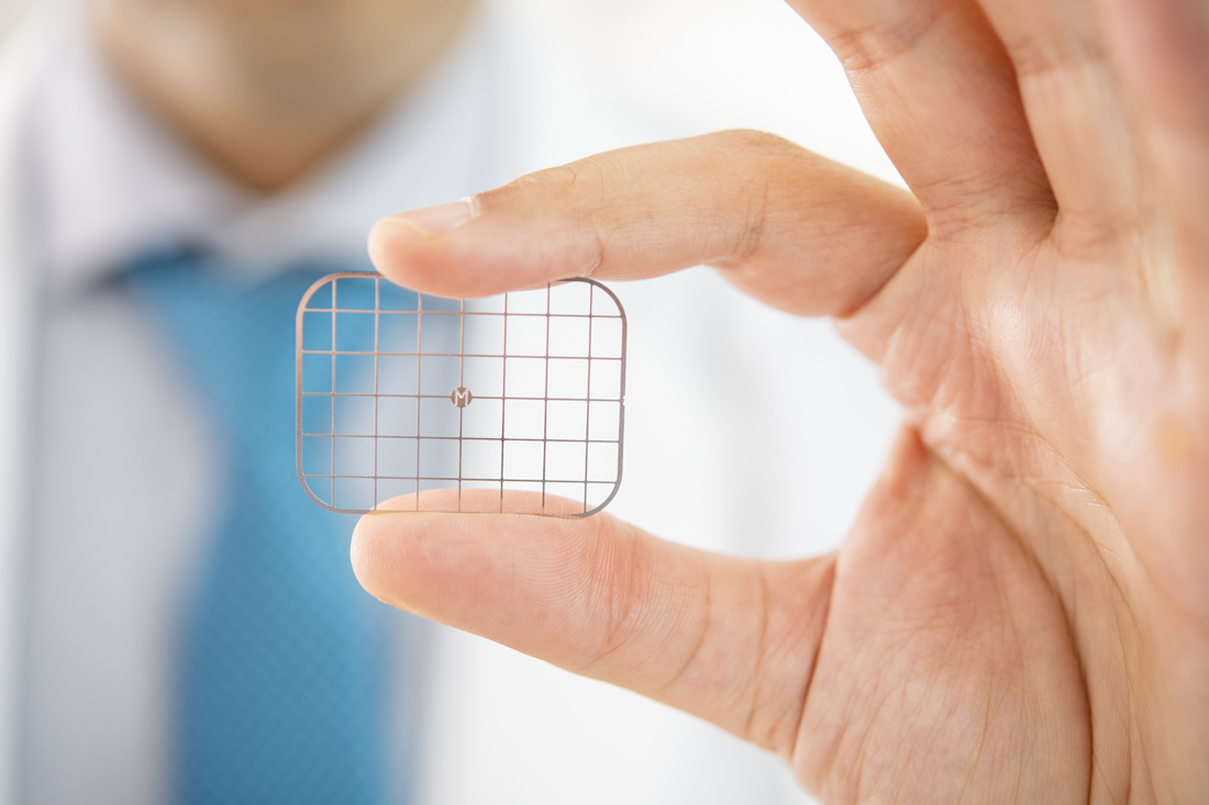 A close up of a small grid, held between Dr. Jalali's thumb and index finger.